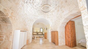 Un pasillo de paredes de piedra que conduce a una sala de estar con un sofá y una puerta de madera.