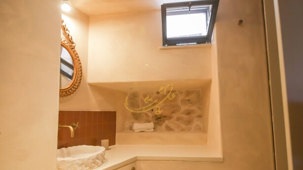 Ein Badezimmer mit Steinwand, Badewanne, Waschbecken und Spiegel.