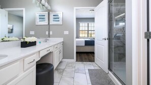 A modern bathroom with a large mirror, white countertops, and a shower area. - Solterra 12bd 11 5bat Sleeps24 Disney Pool Spa (Davenport)