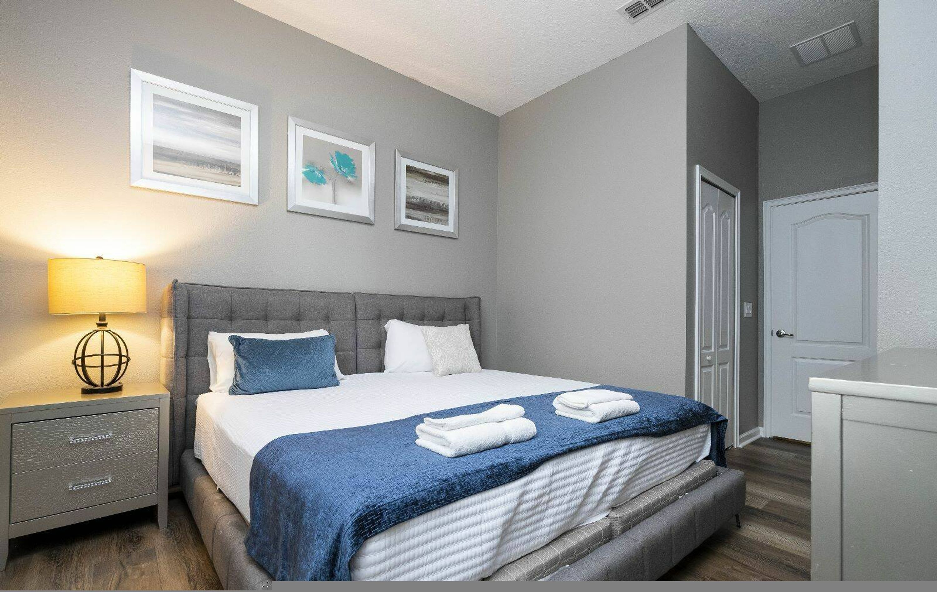 Une chambre bien rangée, avec un lit, une table de chevet et une lampe.