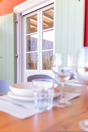 Una mesa de comedor con platos, vasos y una ventana que da a una cerca y árboles.