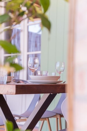 Une table à manger dressée avec des verres à vin, des assiettes et des couverts.
