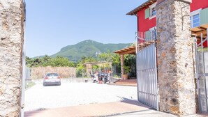 A stone building with a metal gate, a red wall, and a mountain in the background.
