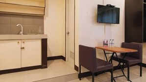 A small kitchenette with a sink, cabinets, and a flat-screen TV mounted on the wall. - RedDoorz @ VCat Apartelle Sampaloc Manila (Quezon City)