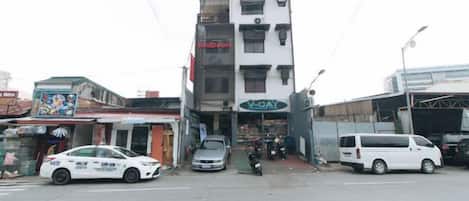 A multi-story building with a storefront on the ground floor, a white van parked in front, and a motorcycle parked to the side.