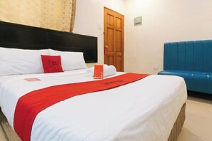 Een hotelkamer met een bed, een houten deur en een blauwe gestoffeerde bank.