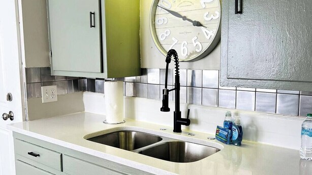 A kitchen with a double sink, a clock, and light green cabinets. - 2 Bedroom Near BP Refinery (Hammond)