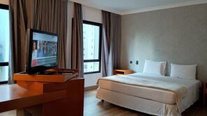 A hotel room with a bed, a desk with a television, and a window with curtains. - GET A FLAT 603 - Luxuoso no Jardins (São Paulo)