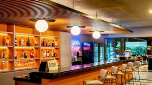 Un'area bar con scaffali pieni di bottiglie di liquore, un neon e sgabelli da bar.