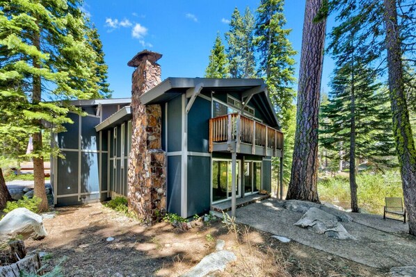 A modern cabin with a stone chimney, large windows, and a wooden deck. - Bear Falls in Alpine Meadows! (Alpine Meadows)
