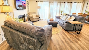 A living room with leather sofas, a television, a fireplace, and a ceiling fan. - Farr Shores Sunset Serenity (Hot Springs)