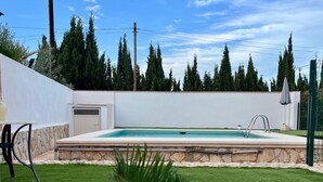 A backyard with a swimming pool, artificial grass, and two white lounge chairs. - Casa Reme, Sencillez y Comodidad Para tu Familia (Playamonte)