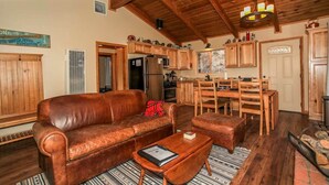 A cozy living room with a leather sofa, wooden dining table, and a fireplace. - Overlook Retreat- Awesome Views, Pets Welcome! (Big Bear City)