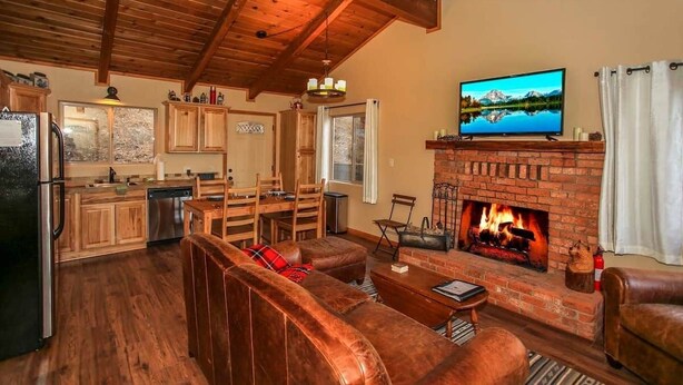 A cozy living room with a fireplace, wooden furniture, and a television. - Overlook Retreat- Awesome Views, Pets Welcome! (Big Bear City)