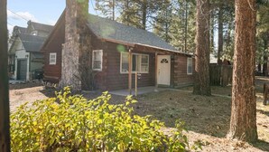 A rustic cabin with a stone chimney, wooden exterior, and a small porch. - On Mountain Time-2bed 1bath+Loft (Big Bear City)