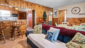 A cozy cabin-style room with a kitchenette, a dining area, and a bed with floral pillows. - On Mountain Time-2bed 1bath+Loft (Big Bear City)
