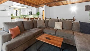 A modern living room with a sectional sofa, a coffee table, and a kitchen in the background. - Dutch Hideaway-3bed W/Gameroom (Big Bear City)