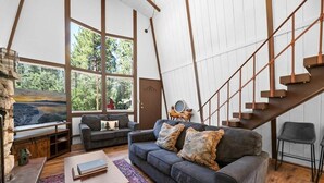 A modern living room with a sofa, coffee table, and a staircase. - Sherwood Cabin-2bed+Loft (Big Bear City)