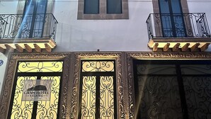 A multi-story hotel with balconies, large windows, and ornate entrance doors.