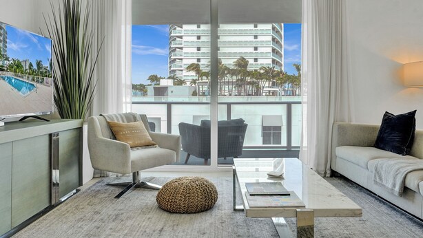 A modern living room with a sofa, armchair, ottoman, and a coffee table.