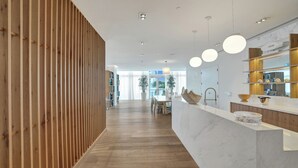A modern kitchen with a wooden panel wall, a marble countertop, and pendant lighting.