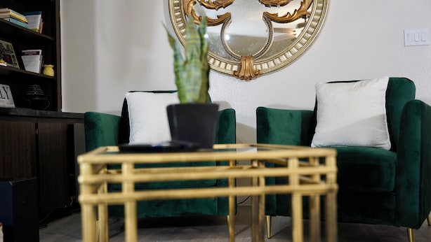 Una sala de estar con un sofá verde, una mesita de centro de madera y una planta en maceta.