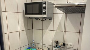 Ett kompakt kök med mikrovågsugn, diskho och ett litet kylskåp.