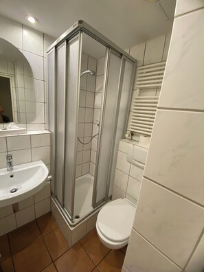 Ein Badezimmer mit Duschkabine, Waschbecken und Toilette.