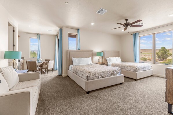 A hotel room with two beds, a desk, and a view of the outdoors.