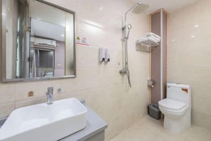 A bathroom with a sink, mirror, shower, and toilet.