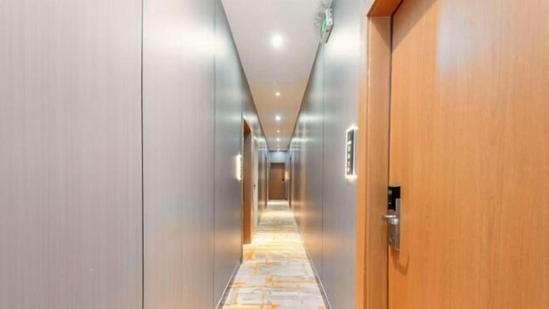 Um corredor com carpete, portas e luminária.