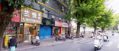 A street with a row of shops, including a restaurant with a visible phone number.