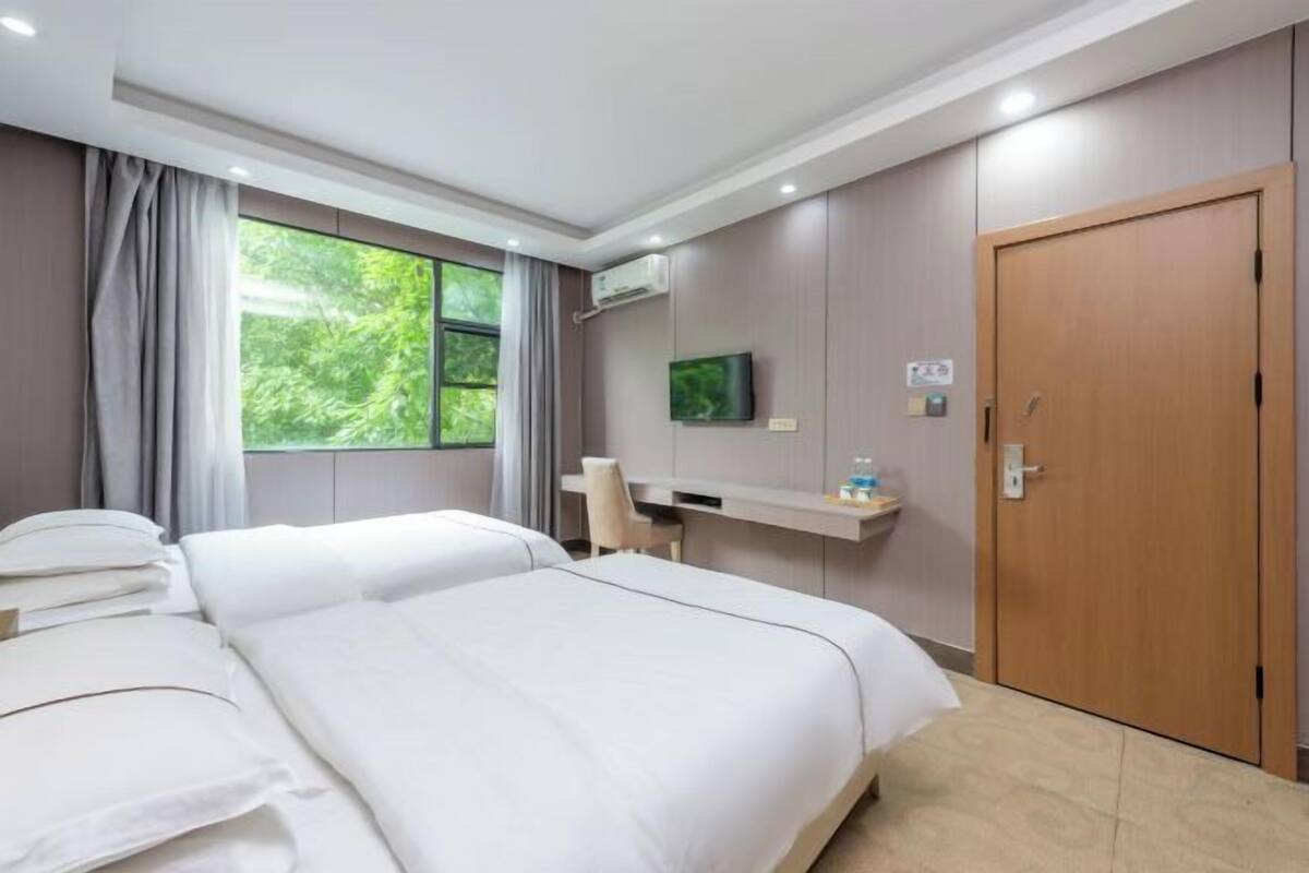 A hotel room with a bed, a desk, a TV, and a door.