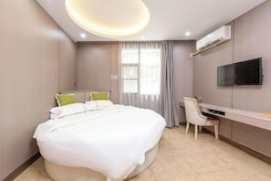 Habitación de hotel moderna con una cama grande, un escritorio, una silla, un televisor y una ventana con cortinas.