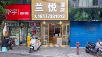 A hotel with a prominent sign, a scooter parked outside, and a blue shutter door.