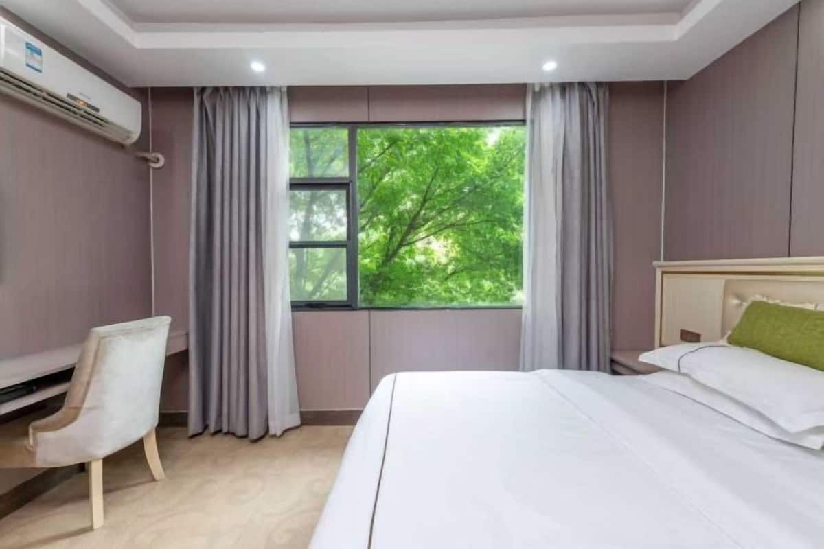 A bedroom with a bed, a desk, and a window with curtains.