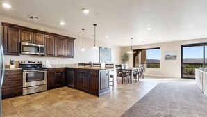 A spacious kitchen with dark wood cabinets, stainless steel appliances, and a large island. - Luxury Desert Playground: Golf View + Resort Access (Hurricane)