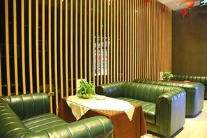 Une pièce avec des canapés en cuir vert, une table en bois ornée d’une plante et des lambris en bois verticaux sur le mur.