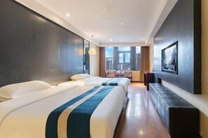 Een hotelkamer met twee bedden, een zithoek met uitzicht en een wandtelevisie.