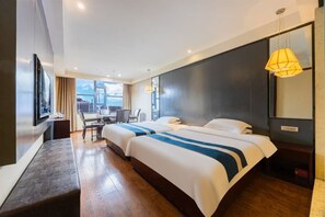 Een hotelkamer met twee bedden, een bureau, een stoel, een televisie en een groot raam.