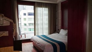 Ein Hotelzimmer mit Bett, einem Badezimmer mit Waschbecken und Blick auf ein Gebäude durch ein Fenster.