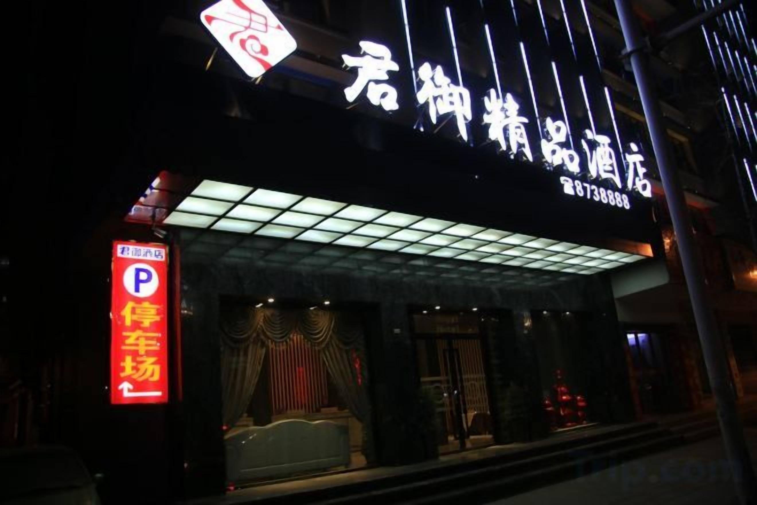 A hotel entrance with a neon sign, a parking sign, and a covered entrance area.