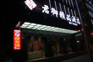 A hotel entrance with a neon sign, a parking sign, and a covered entrance area.