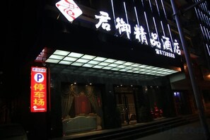 Een hotel ingang met een neonbord, een parkeerbord en een overdekte entree.