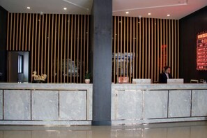 A reception area with a marble counter, vertical wooden slats, and a digital display. - Junyu Boutique Hotel (Wanyuan Railway Station) (Wanyuan)
