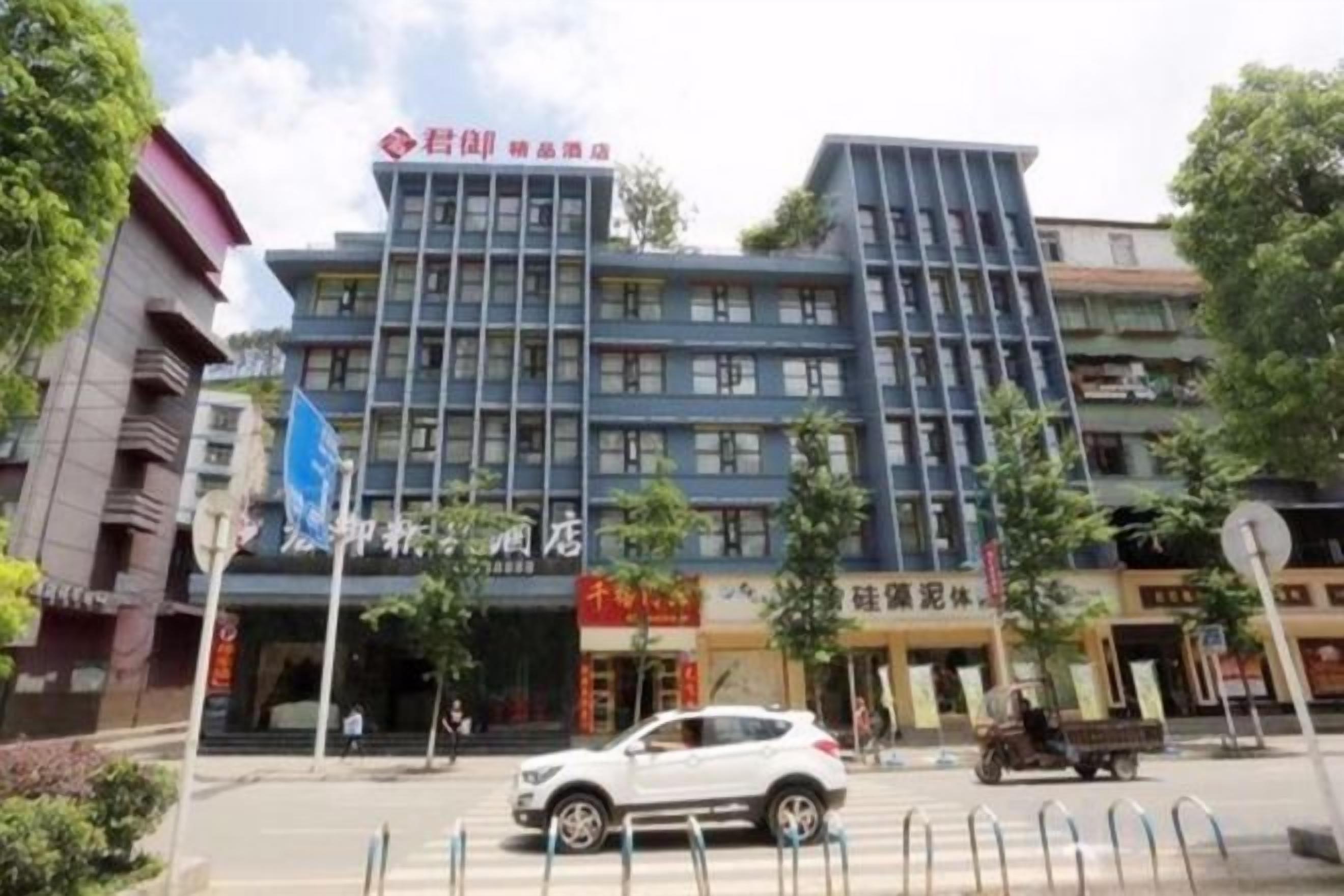 A multi-story building with a prominent entrance, a flag, and a signboard.