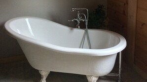 A freestanding bathtub in a room with wooden walls and a tiled floor. - Cottage life in Quebec  (Morin-Heights)