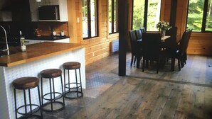 A kitchen with a bar area, wooden flooring, and large windows. - Cottage life in Quebec  (Morin-Heights)