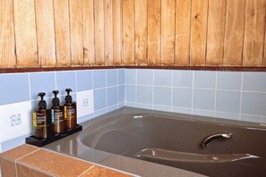 A bathroom with a bathtub, wooden wall paneling, and blue tiles. - Vacation Rental Shirayuri (Ito)