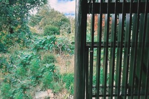 A view through a metal gate with greenery and a stone wall in the background.